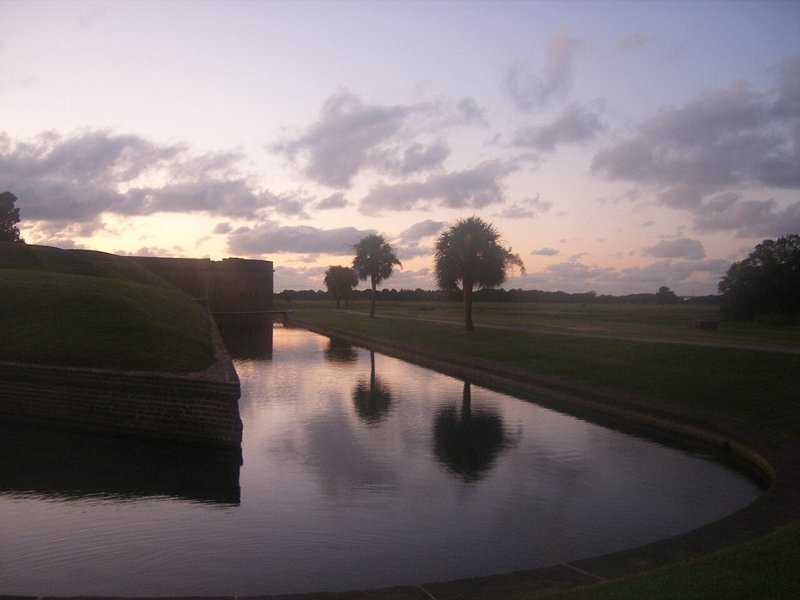 A purple dawn sky and palms reflected in the still moat at Fort Pulaski near Savannah.